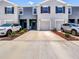 Townhome exterior featuring a well-manicured lawn, gray paint, and matching one-car garages at 32977 Kaloko Rd, Wesley Chapel, FL 33543