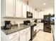 Well-lit kitchen with white cabinets, granite countertops, tile floors, and black appliances at 32977 Kaloko Rd, Wesley Chapel, FL 33543