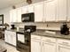 Charming kitchen with granite countertops, white cabinets, and black appliances at 32977 Kaloko Rd, Wesley Chapel, FL 33543