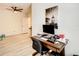 Office featuring wood-look floors, ceiling fan, practical desk setup, and a view into the hallway at 32977 Kaloko Rd, Wesley Chapel, FL 33543