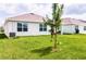 Spacious backyard with lush green grass, an AC unit, and partial views of other houses and a tree at 33668 Elm Hill Branch, Wesley Chapel, FL 33545