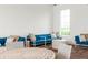 Bright seating area with comfortable blue sofas, pillows, and a round white table by a bright sunny window at 33668 Elm Hill Branch, Wesley Chapel, FL 33545