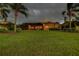 Wide shot of the backyard with a large grassy area, trees, and screened lanai at 3895 Mimosa Pl, Palm Harbor, FL 34685