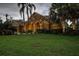 Inviting home featuring lush landscaping, palm trees, an arched entryway and a two-car garage at 3895 Mimosa Pl, Palm Harbor, FL 34685