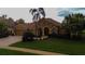 Charming home with well-manicured lawn, arched entryway, and lush tropical landscaping at 3895 Mimosa Pl, Palm Harbor, FL 34685
