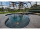 Screened pool with attached spa overlooks beautiful lawn, landscaping, and lake at 3895 Mimosa Pl, Palm Harbor, FL 34685