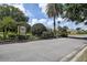 Community entrance featuring lush landscaping, mature trees, and a prominent street sign at 3895 Mimosa Pl, Palm Harbor, FL 34685