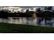 Scenic lake view featuring a fountain, surrounded by lush greenery and neighboring homes at dusk at 3895 Mimosa Pl, Palm Harbor, FL 34685