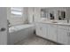 Serene bathroom with a soaking tub, double vanity, and stylish tile flooring in a soothing neutral palette at 4077 Cadence Loop, Land O Lakes, FL 34638