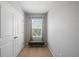 Hallway with a window, neutral carpet, base trim, and a grey upholstered bench with wooden legs at 4504 Silver Lining St, Sarasota, FL 34238