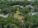 Aerial perspective of the property surrounded by lush greenery, featuring the main house and outbuildings at 5926 Frontier Dr, Zephyrhills, FL 33540