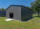 View of metal building and garage surrounded by a green lawn on a sunny day at 5926 Frontier Dr, Zephyrhills, FL 33540