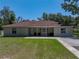 A ranch-style home featuring a welcoming covered porch and an inviting front lawn, surrounded by mature trees at 5926 Frontier Dr, Zephyrhills, FL 33540