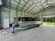 Spacious metal building interior with a pontoon boat parked inside and open garage door at 5926 Frontier Dr, Zephyrhills, FL 33540