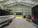 View of the metal building interior showing boat, tires, lawn mower, and door to the exterior at 5926 Frontier Dr, Zephyrhills, FL 33540