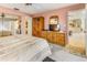 Well-lit bedroom features a neutral carpet, wooden dresser, and a view into the kitchen at 70 Morning Dove Pl, Oldsmar, FL 34677