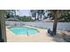 Outdoor pool area surrounded by a tall fence, mature trees, and a peaceful seating area at 7515 Brookhaven Ct, Tampa, FL 33634