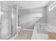Bathroom with a glass-enclosed shower, soaking tub, white tiling, and neutral-colored tile flooring at 8806 Bayaud Dr, Tampa, FL 33626