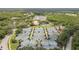 Extensive aerial view of tennis courts, a lake with a fountain, green space, and multiple buildings surrounded by lush trees at 9327 Hunters Park Way, Tampa, FL 33647