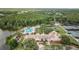 Aerial view of community amenities, featuring a pool, lake, mini-golf, tennis courts, and clubhouse surrounded by mature trees at 9327 Hunters Park Way, Tampa, FL 33647