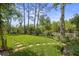 Private backyard featuring green grass, a white fence, mature trees, and serene natural surroundings at 9327 Hunters Park Way, Tampa, FL 33647