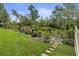 Backyard featuring an expansive lawn area and a stone pathway through a landscaped garden with an array of bushes and plants at 9327 Hunters Park Way, Tampa, FL 33647