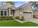 Charming exterior view of a beige home with a well-maintained lawn, landscaping, and an attached two-car garage at 9327 Hunters Park Way, Tampa, FL 33647