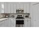 Contemporary kitchen featuring stainless steel oven and microwave, white cabinets, and granite countertops at 9327 Hunters Park Way, Tampa, FL 33647