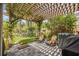Stone patio shaded by a wooden pergola featuring an outdoor seating area with a grill, two chairs, and lush landscaping at 9327 Hunters Park Way, Tampa, FL 33647
