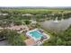 Aerial view of a community pool area featuring a large pool, deck chairs, a playground, and manicured lawns next to a lake at 9327 Hunters Park Way, Tampa, FL 33647