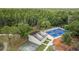 Aerial view featuring a wall ball court and neighboring tennis courts against a backdrop of dense, verdant trees at 9327 Hunters Park Way, Tampa, FL 33647