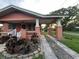 Side view of a house with a covered porch, driveway, mature landscaping, and charming brickwork at 9907 Maggie St, Gibsonton, FL 33534