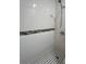 Bright shower with a unique tile accent stripe and a black and white tile floor at 9907 Maggie St, Gibsonton, FL 33534