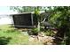 Home's backyard featuring a screened-in porch addition, seen through trees and green grass at 10871 86Th Ave, Seminole, FL 33772