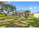 Large backyard featuring a screened in lanai, a big oak tree, and green grass at 1178 Fraser Pine Blvd, Sarasota, FL 34240