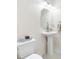 A minimalist bathroom features a pedestal sink, octagon mirror, and white fixtures for a clean, modern look at 1178 Fraser Pine Blvd, Sarasota, FL 34240