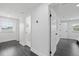 Bright hallway with gray laminate flooring leads to doorways with white trim and a view from the window at 1413 E 108Th Ave, Tampa, FL 33612