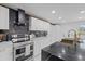 Modern kitchen boasts stainless steel appliances, sleek black countertops, and white cabinetry with gold hardware at 1413 E 108Th Ave, Tampa, FL 33612