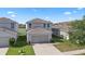 Aerial shot of a two-story home with a neutral color scheme, a two-car garage, and landscaping at 14403 Dunrobin Dr, Wimauma, FL 33598