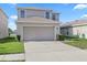 Inviting two-story home features a two-car garage, well-maintained lawn, and a concrete driveway at 14403 Dunrobin Dr, Wimauma, FL 33598