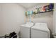 Well-lit laundry room with modern appliances and storage shelves for convenience and organization at 14460 English Lavender Dr, Wimauma, FL 33598