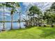 Picturesque backyard featuring lush green grass and mature trees overlooking a lake with docks under a partly cloudy sky at 15012 Maurine Cove Ln, Odessa, FL 33556