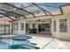 View of a backyard pool with inset spa and patio area inside a screened enclosure, with a lake in the background at 15012 Maurine Cove Ln, Odessa, FL 33556