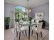Formal dining room with a glass table, six upholstered chairs, a modern chandelier, and a large arched window with curtains at 15012 Maurine Cove Ln, Odessa, FL 33556