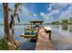 Beautiful boat dock with a wooden deck, covered seating area, and personal watercraft, overlooking a tranquil lake at 15012 Maurine Cove Ln, Odessa, FL 33556