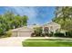 Attractive single-story home with manicured lawn, mature trees, and a three-car garage at 15012 Maurine Cove Ln, Odessa, FL 33556