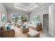 Bright living room with wicker furniture, a glass coffee table, and a view of the screened-in pool and lake at 15012 Maurine Cove Ln, Odessa, FL 33556