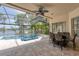 Screened-in patio features a ceiling fan, a dining set, and a pool with a built-in spa overlooking a lake at 15012 Maurine Cove Ln, Odessa, FL 33556