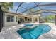 Beautiful backyard pool with an inset spa inside a screened enclosure, with a lake in the background at 15012 Maurine Cove Ln, Odessa, FL 33556