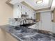 Modern kitchen features granite countertops, white cabinets, and a stylish backsplash at 1881 Lichen Ln # B, Clearwater, FL 33760